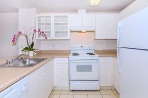 Seattle apartment for rent - A white kitchen with a stove, sink, and cabinets.