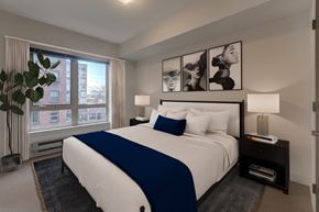 Seattle apartment for rent - A bedroom with a large bed and a window overlooking a city.