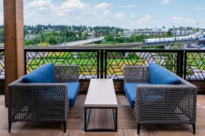 Seatac apartment for rent - A balcony with a table and two chairs with a view of a highway and buildings.