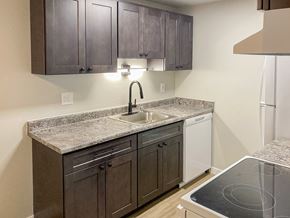 Federal Way apartment for rent - A kitchen with a granite countertop and dark brown cabinets.