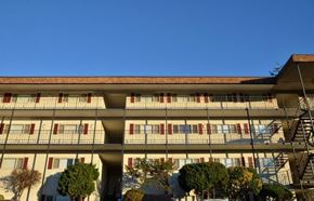 Shoreline apartment for rent - A large building with a red roof and white walls with balconies.
