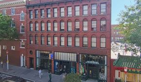 Seattle apartment for rent - A red brick building with a green roof and a blue sign on the ground floor.