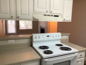Seattle apartment for rent - A white stove with four burners is in a kitchen with white cabinets.