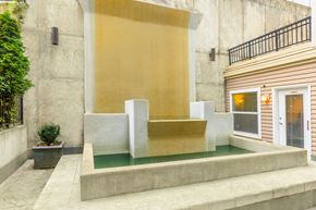 Seattle apartment for rent - A modern house with a yellow wall and a small pool in front.