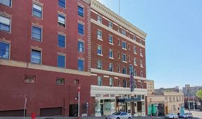 Seattle apartment for rent - A red brick building with a blue awning sits on a street corner.