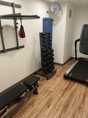 Seattle apartment for rent - A gym room with a treadmill, bench, weights and a hanging leg curl.