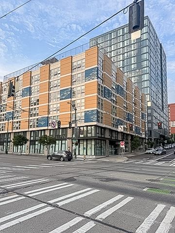 Seattle apartment for rent - A modern building with orange and beige panels is situated on a street corner with a car parked on the side of the road.