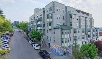 Seattle apartment for rent - A street view of a residential area with apartment buildings and parked cars.