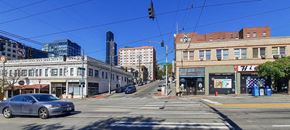 Seattle apartment for rent - A street view with a car on the road and buildings on the side.