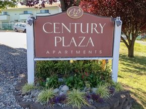Burien apartment for rent - A sign for Century Plaza Apartments is surrounded by plants and flowers.