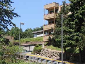 Tukwila apartment for rent - A modern building with balconies is surrounded by trees and greenery.
