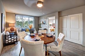 Renton apartment for rent - A dining room with a table set for two and a view of trees outside the window.