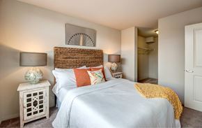 Renton apartment for rent - A bedroom with a white bed and a wicker headboard.