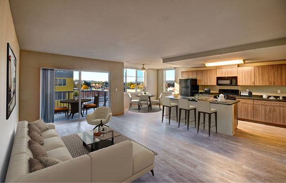 Renton apartment for rent - A modern living room with a large couch and a kitchen area in the background.
