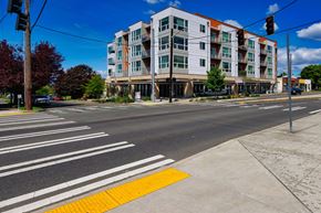 Seattle apartment for rent - A multi-story building with a red and white facade is situated on a street corner with a crosswalk in front of it.