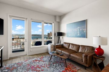 Tacoma apartment for rent - A living room with a brown leather couch, a red lamp, and a painting on the wall.
