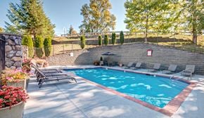 Bothell apartment for rent - A pool surrounded by a stone wall and trees.