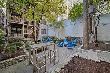 Chicago apartment for rent - A patio with a table and chairs is surrounded by a brick wall and trees.