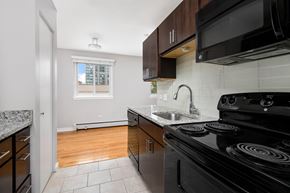 Chicago apartment for rent - a kitchen with granite counter tops, brown cabinets and black appliances