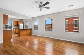 Chicago apartment for rent - an empty living room with a ceiling fan and a kitchen