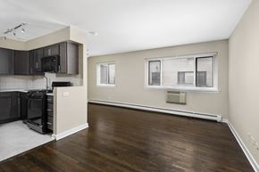 Chicago apartment for rent - an empty living room and kitchen with wood flooring and black appliances