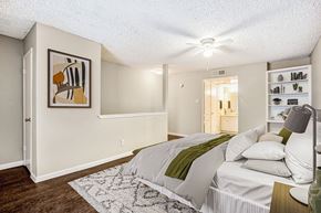 Dallas apartment for rent - A bedroom with a bed, a painting on the wall, and a rug on the floor.