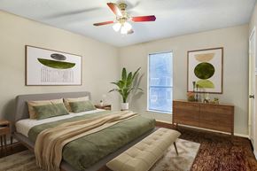 Dallas apartment for rent - A bedroom with a bed, a dresser, and a ceiling fan.