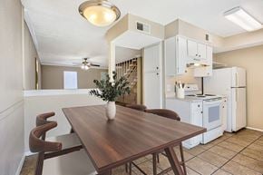 Dallas apartment for rent - A kitchen with a table and chairs in the foreground and a refrigerator, microwave, and oven in the background.
