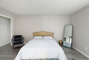 Wichita apartment for rent - A bedroom with a large bed, a chair, and a mirror.