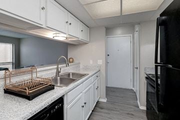 Wichita apartment for rent - A kitchen with white cabinets and a black refrigerator.