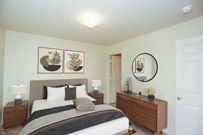 Baton Rouge apartment for rent - A bedroom with a bed, nightstand, and a mirror with a plant on it.