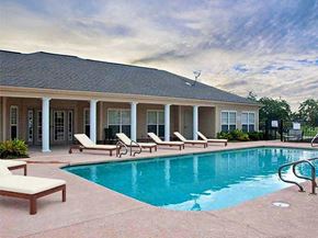 Baton Rouge apartment for rent - A pool area with sun loungers and a house in the background.