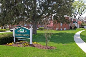 Baltimore apartment for rent - A sign for Greenwich Gardens is in the foreground of a well kept lawn.