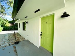 Miami triplex for rent - A green door is on the side of a white building.