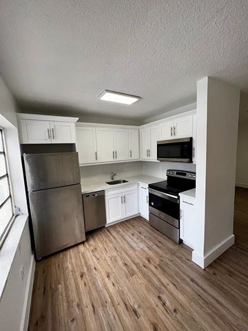 Miami apartment for rent - A kitchen with white cabinets and a wooden floor.