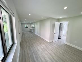 Miami triplex for rent - A long, empty room with wood flooring and white walls.