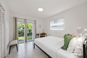 Miami apartment for rent - A bedroom with a bed, nightstand, and chair.