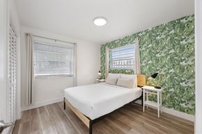 Miami apartment for rent - A bedroom with a bed, nightstand, and a wallpapered wall.