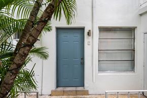 Miami apartment for rent - A blue door is on the left side of a white building.