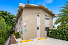Miami apartment for rent - A beige building with a blue sign on the front.