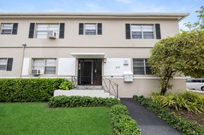 Miami apartment for rent - A beige building with black shutters and a black door.