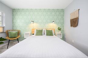 Miami apartment for rent - A bedroom with a white bed and green patterned wallpaper.