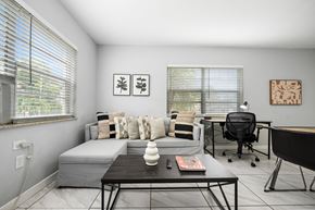 Miami apartment for rent - A modern living room with a grey couch, a black coffee table, and a black chair.