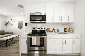 Pompano Beach apartment for rent - A modern kitchen with white cabinets and a stainless steel oven.
