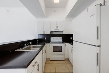 Miami apartment for rent - A kitchen with white cabinets and black countertops.