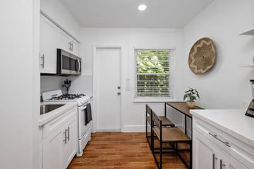 Miami apartment for rent - A kitchen with white cabinets and a wooden floor.