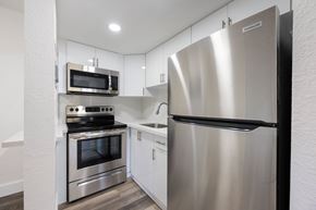 Miami apartment for rent - A modern kitchen with stainless steel appliances and white cabinetry.