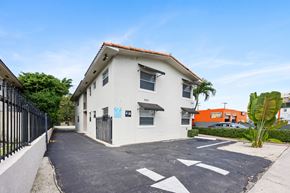 Miami apartment for rent - A white house with a black gate and a driveway with white arrows painted on it.