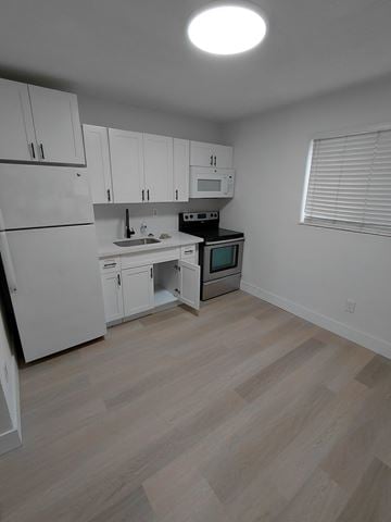 Miami apartment for rent - A kitchen with white cabinets and a wooden floor.