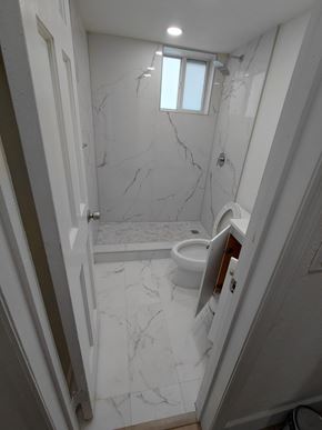 Miami apartment for rent - A white bathroom with a marble floor and walls.